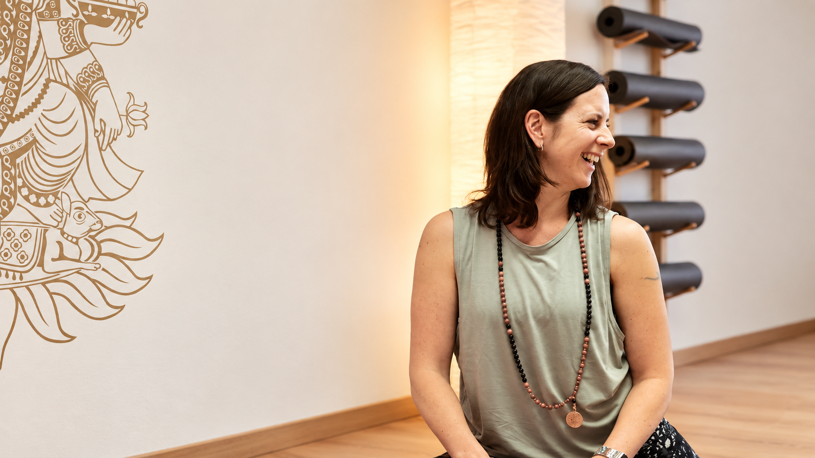 Jessica Szymanski lächelt in einem warm beleuchteten Yogastudio